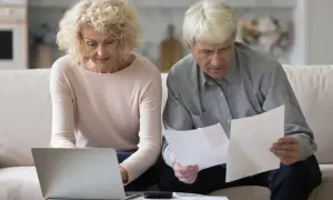 Para planuje emeryturę pomostową, analizując dokumenty i korzystając z laptopa.