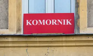 Czerwony szyld z napisem "KOMORNIK" nad oknem. Może to oznaczać, że komornik sądowy działa w tym miejscu, a kwota wolna od zajęcia jest chroniona.