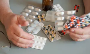 Ręce seniora trzymają opakowania z lekami. Dostępne są darmowe leki dla seniorów, co ułatwia dbanie o zdrowie.