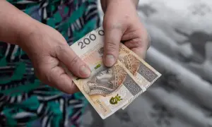 Dwie stuzłotówki w dłoniach, symbol wsparcia z MOPS. Zasiłek pielęgnacyjny na codzienne potrzeby.