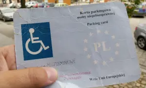 Karta parkingowa dla niepełnosprawnych z symbolem wózka inwalidzkiego i oznaczeniem PL. Dokument uprawnia do parkowania w całej Unii Europejskiej.