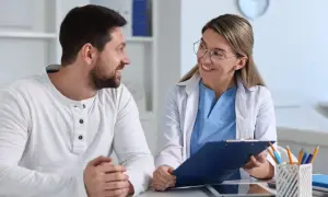 Lekarka omawia z pacjentem refundację okularów przez pracodawcę. Uśmiechnięta lekarka z okularami trzyma dokumenty.