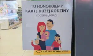Plakat informuje, że honorowana jest karta dużej rodziny. Widnieje na nim rysunek rodziny z dwójką dzieci i niemowlęciem.