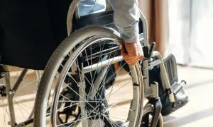 Dłoń osoby niepełnosprawnej chwyta obręcz wózka inwalidzkiego, gotowa do samodzielnego ruchu.