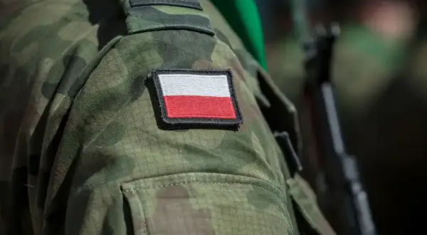 Żołnierz w mundurze moro z polską flagą na ramieniu, gotowy do służby, symbolizuje dumę i poświęcenie, które towarzyszą emerytura wojskowa.
