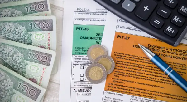Pieniądze, kalkulator i formularze podatkowe PIT. Przygotowanie do rozliczenia sprzedaży samochodu i zapłaty podatku.