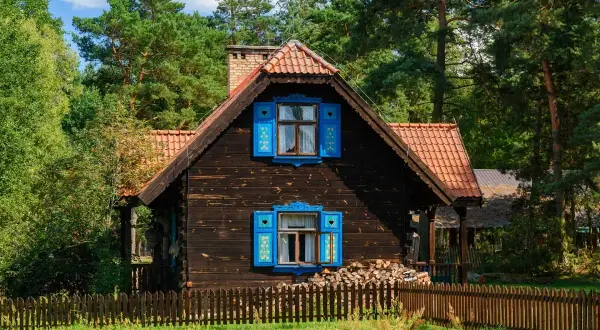 Drewniany dom z niebieskimi okiennicami, idealny na wypoczynek z podlaskim bonem turystycznym 2026.