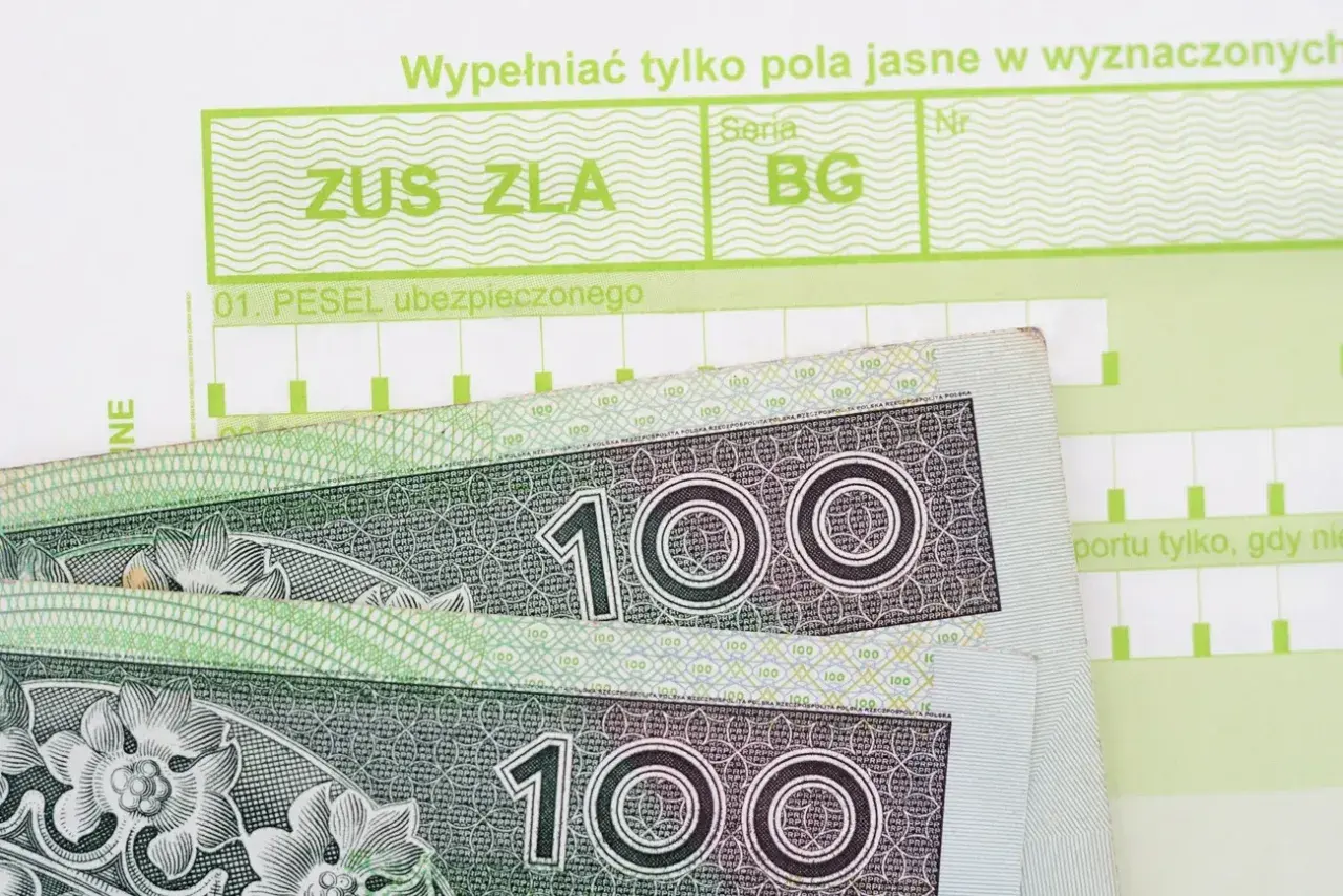 ZUS ZLA i banknoty 100 zł. Dokumenty związane z ubezpieczeniem społecznym, które pomagają ustalić, ile wynosi zasiłek chorobowy.