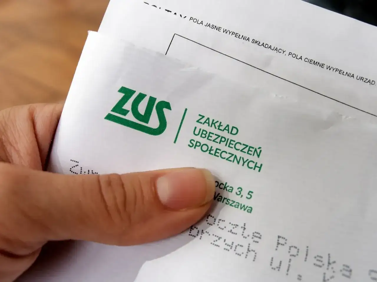 Dłoń trzyma dokument ZUS. Czas na odprawę emerytalną i formalności.