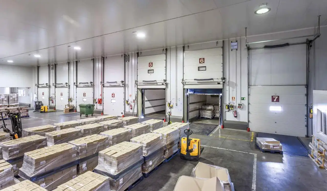 Magazyn z paletami towarów i bramami załadunkowymi. System fifo zapewnia sprawny obieg produktów.