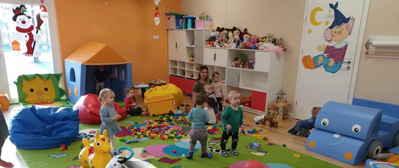 Dzieci bawią się klockami w kolorowym żłobku, gdzie dofinansowanie do żłobka zapewnia im bezpieczną i radosną przestrzeń do rozwoju.