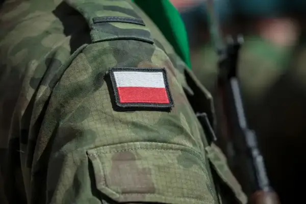 Żołnierz w mundurze moro z polską flagą na ramieniu, gotowy do służby, symbolizuje dumę i poświęcenie, które towarzyszą emerytura wojskowa.