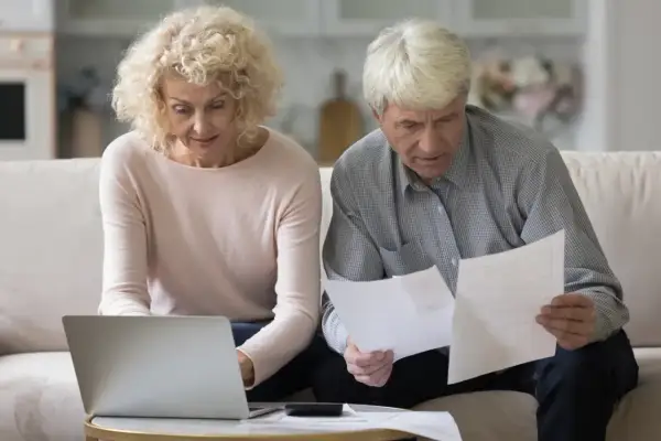 Para planuje emeryturę pomostową, analizując dokumenty i korzystając z laptopa.