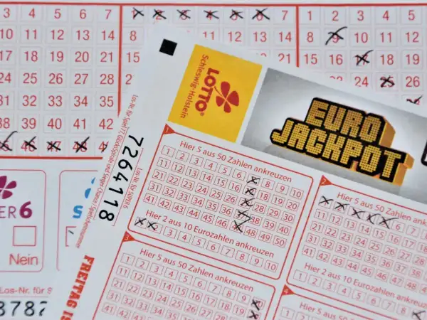 Kupony lotto z zaznaczonymi liczbami i logo Eurojackpot. Zastanawiasz się, ile podatku od wygranej zapłacisz?