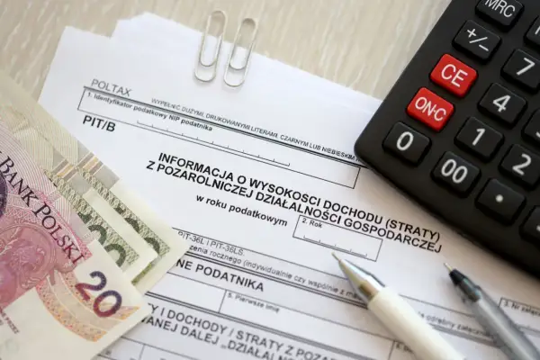 Polskie banknoty, kalkulator i formularz PIT/B. Kto to rezydent podatkowy? To osoba, która rozlicza się z dochodów w Polsce.