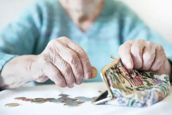 Dłonie starszej osoby liczą monety do portmonetki. Czy mam 60 lat i 20 lat pracy, czy dostanę emeryturę?