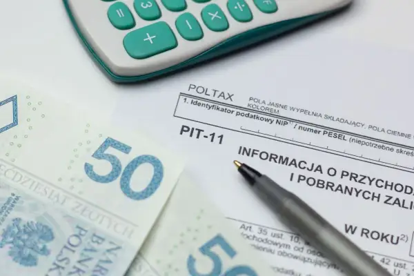 Kalkulator, długopis, banknoty 50 zł i formularz PIT-11.